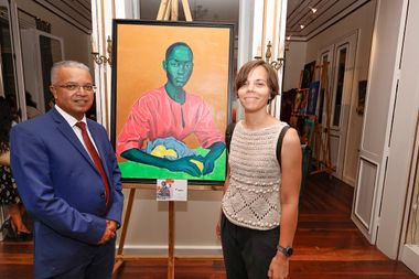 Marine Hibert pose devant son tableau intitulé Rachel (un portrait aux couleurs vives qui tient une pomme) en compagnie du président du département.