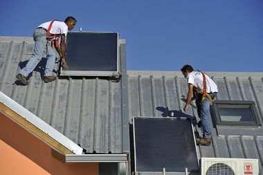 ouvriers posant des panneaux solaires pour chauffe eau sur un toit de l'ile de la Reunion